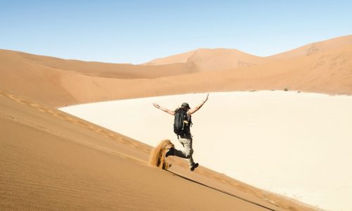 Majestic shot of woman running down a dune on the way to Deadvlei, Namibia