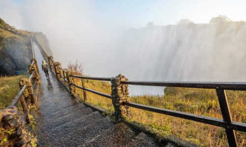 Person walking along boardwalk at Victoria Falls in Zimbabwe.