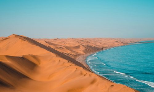 Aerial view of Namibian coastline where massive dunes meet ocean