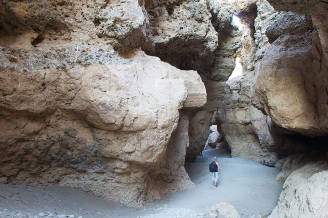 the back of a person walking on the sand in a canyon