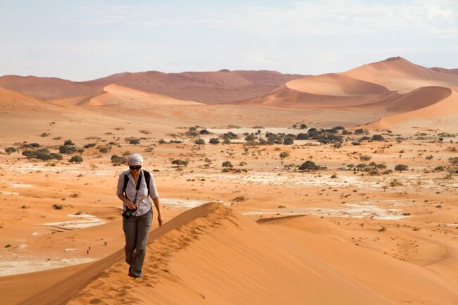 Hiker on top of Sossusvlei dune with serene desert background