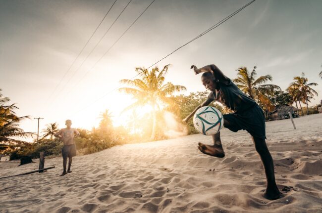 Mozambique local boys playing football on beach