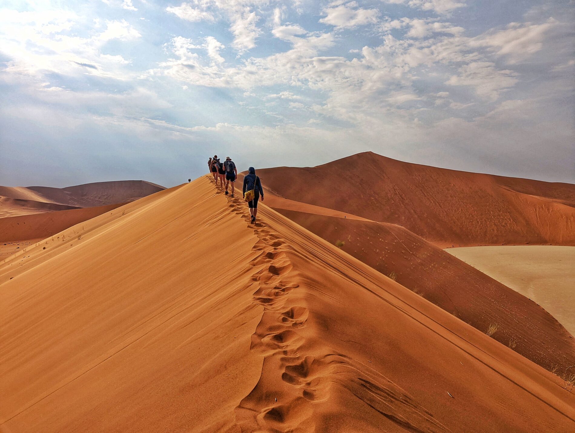 Group of tourists walking on top of desert dunes in Namibia