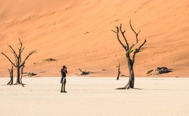 Lonely adventure travel photographer at Deadvlei crater in Sossusvlei territory - Namibian world famous desert