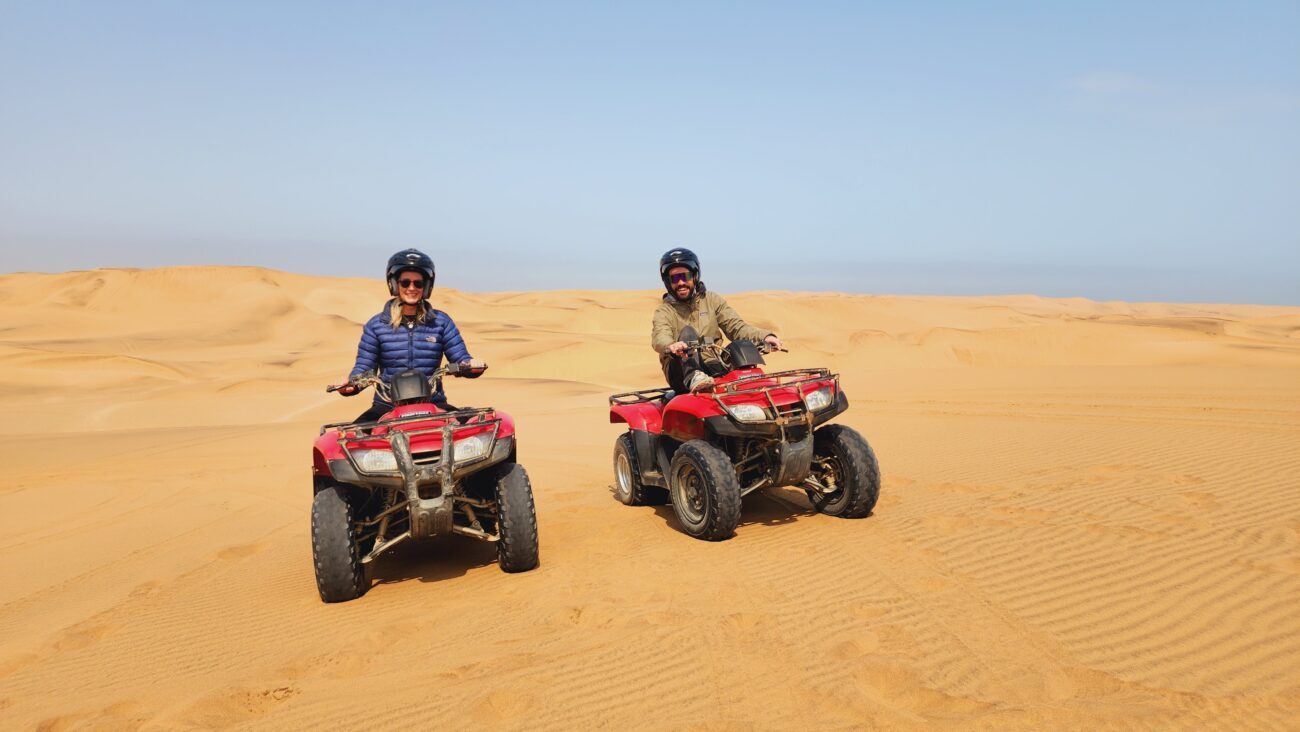 Happy couple poses on quad bikes in desert of Swakopmund.