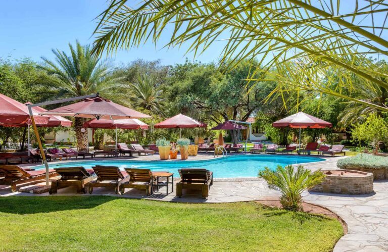 view of a swimming pool with sun chairs and umbrellas