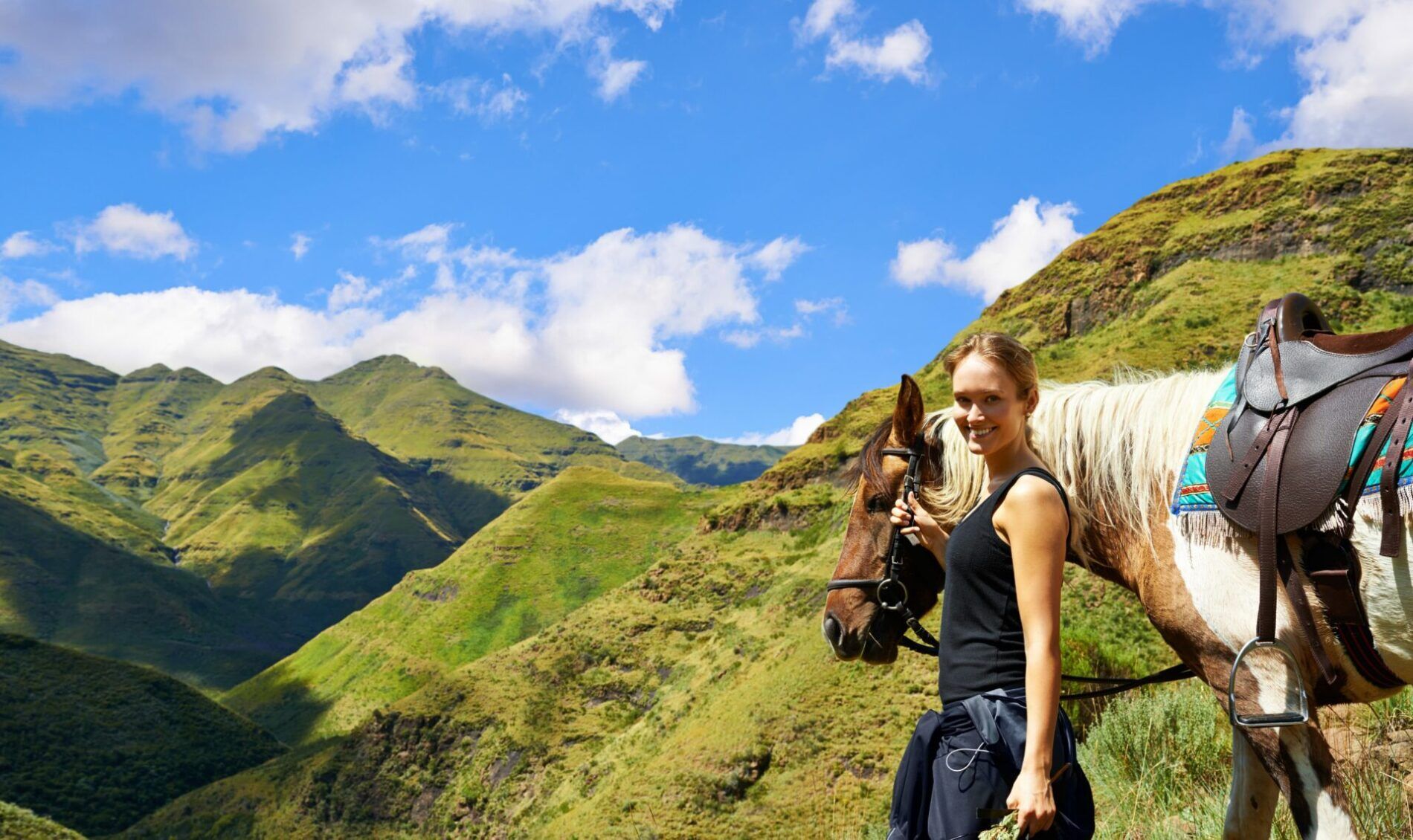 On top of the world - young woman with her horse on a mountain trek