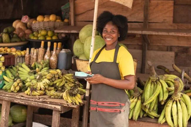 A smiling African lady selling fruits and vegetables in a market