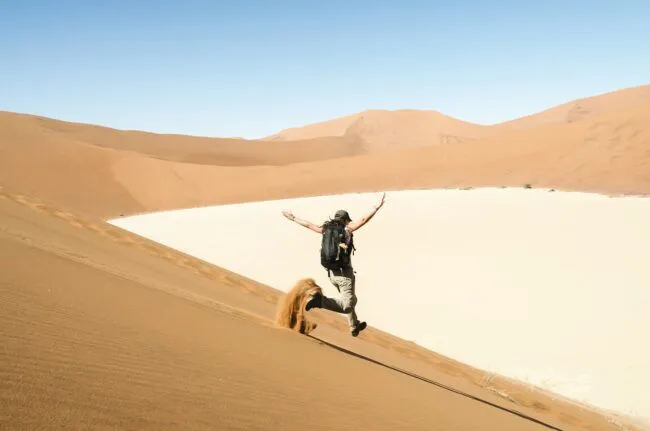 Majestic shot of woman running down a dune on the way to Deadvlei, Namibia