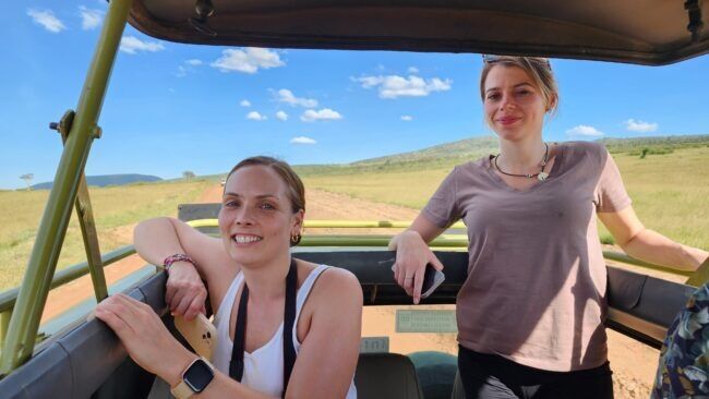 Two female safari guests posing for camera from popup jeep