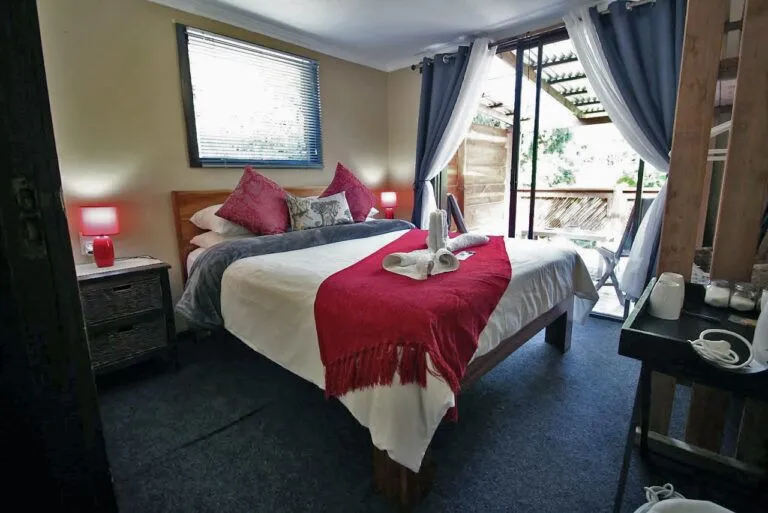 inside of a bedroom with a bed, bedside cabinets, lamps and a coffee station