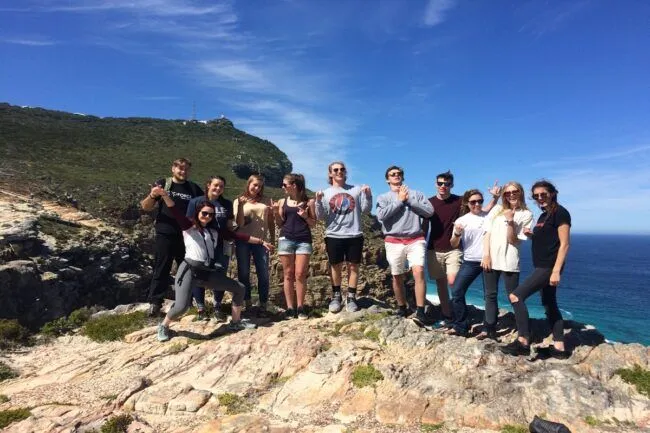 group of tourists posing on a cliff overlooking the sea