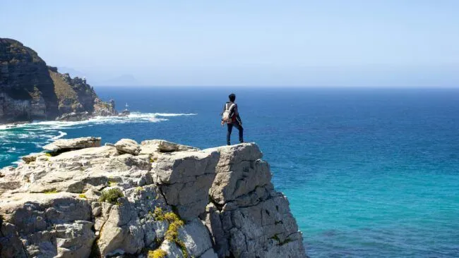 a person standing on a cliff looking out at the ocean