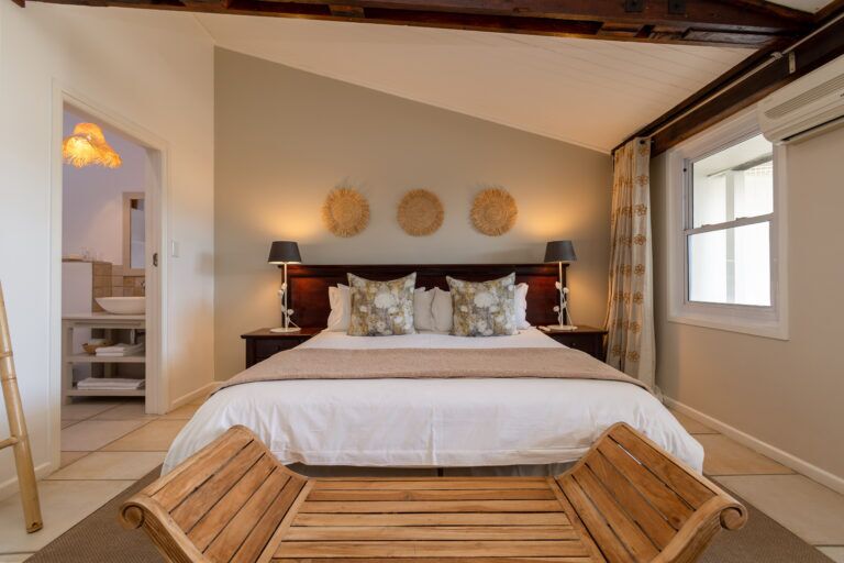 a bedroom with a double bed, bench and en suite bathroomj