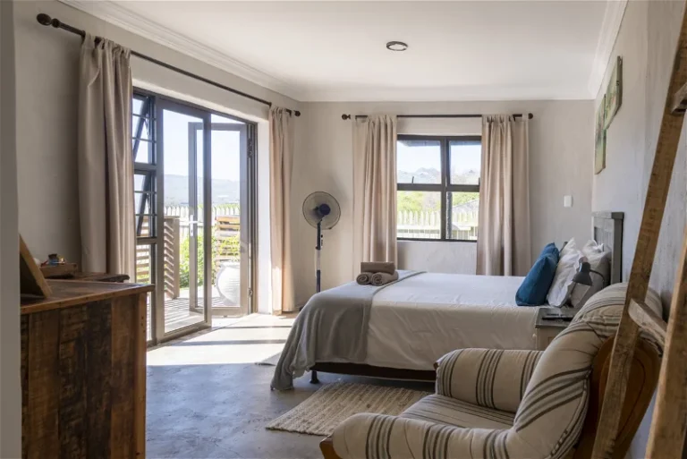 a bedroom with a bed, armchair, tables and fan