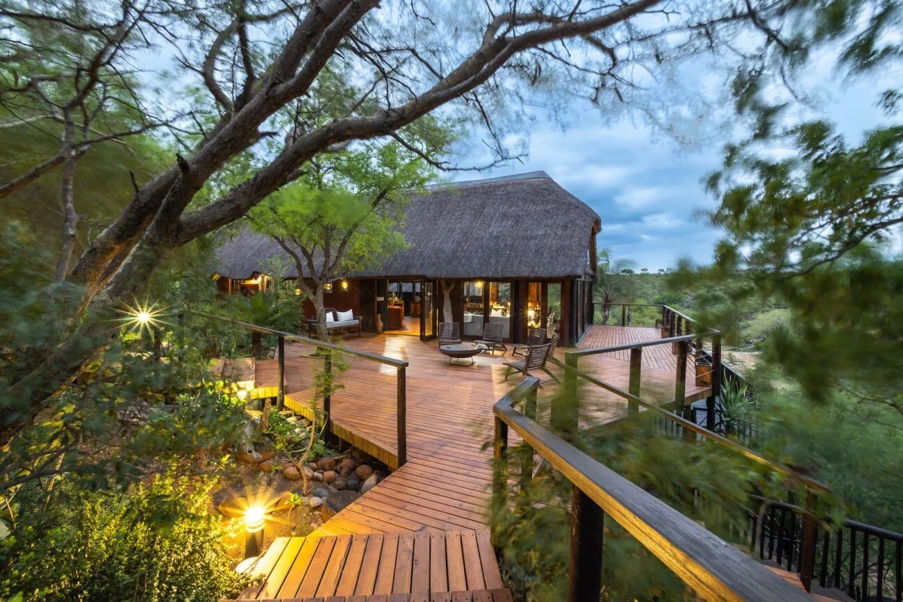 a beautiful lodge with a sitting area and fire pit with views of the bush