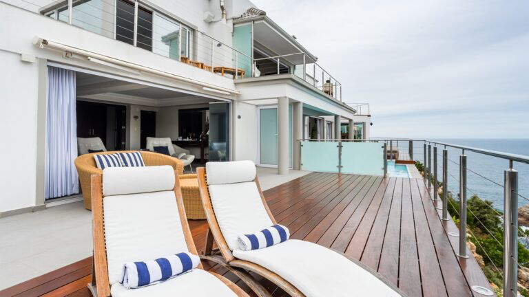 a deck with two sun chairs with the view of the sea in the background