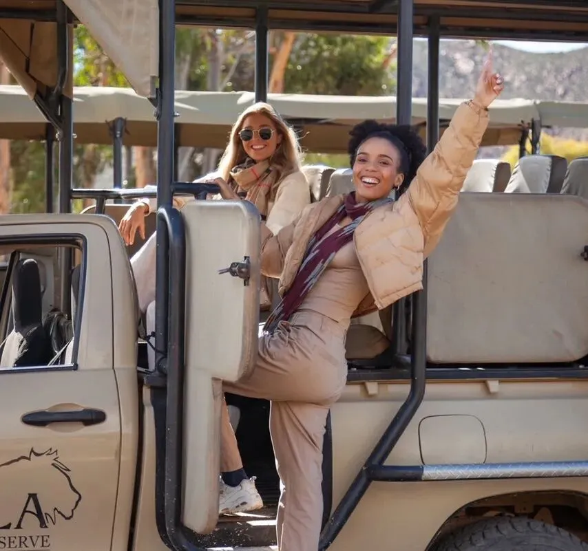 a lady posing on the side of a safari vehicle