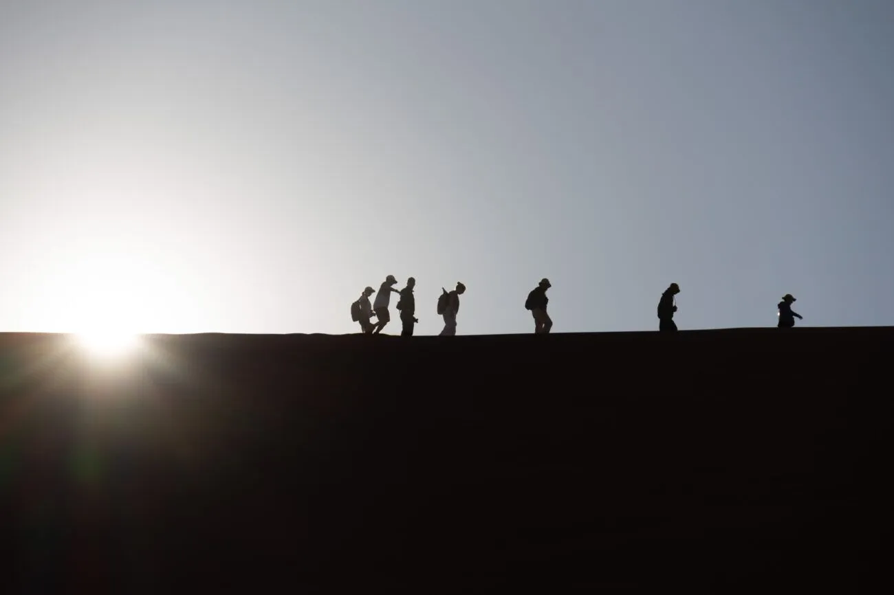 silhouette of people walking on a dune