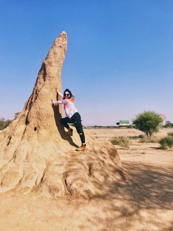 woman leaning against a termite mount
