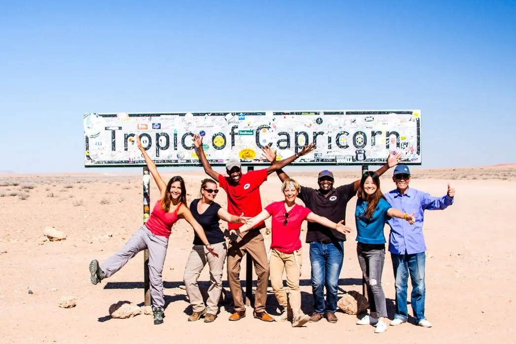 people standing in front of the tropic of Capricorn sign