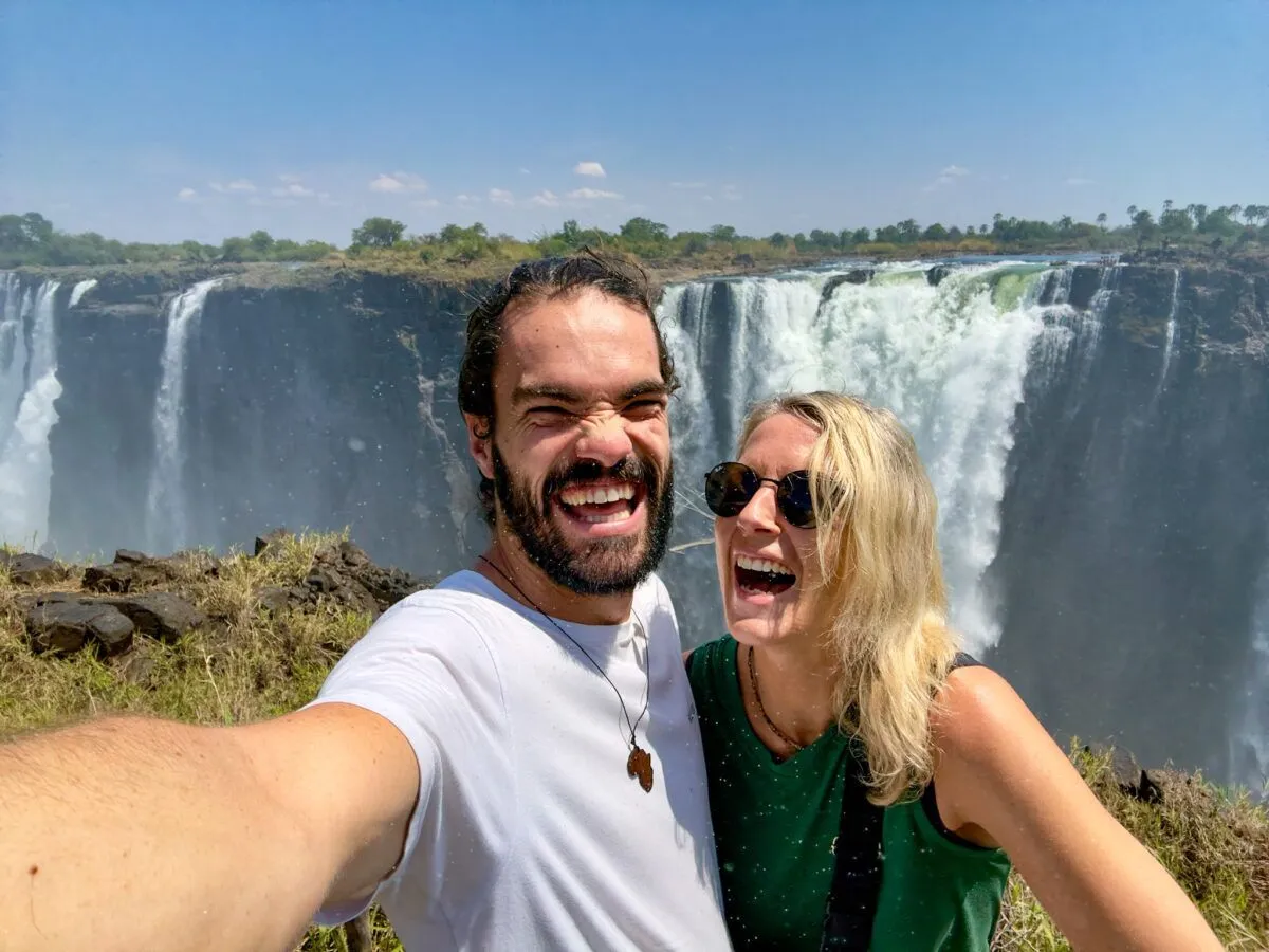 Happy couple laughing with Victoria Falls in the background.