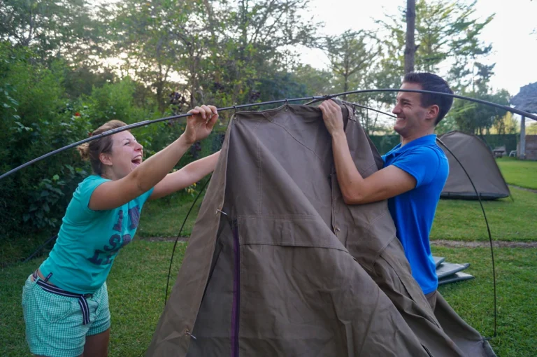 Two campers setting up canvas tent
