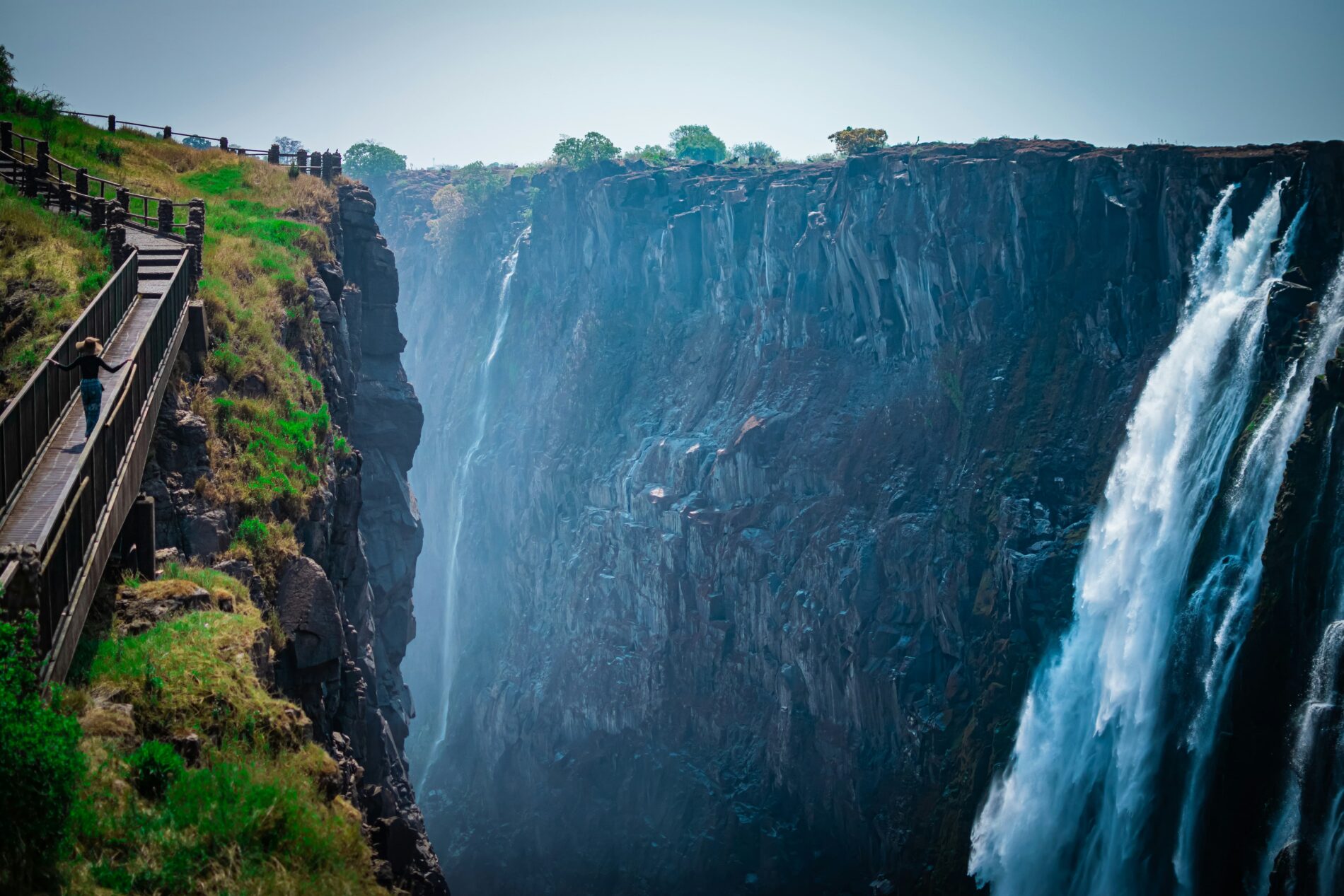 Female walks along boardwalk at Victoria Falls waterfall.