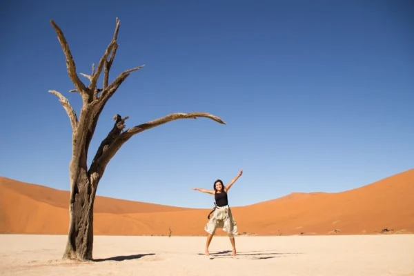 Traveler posing next to tree in deadvlei