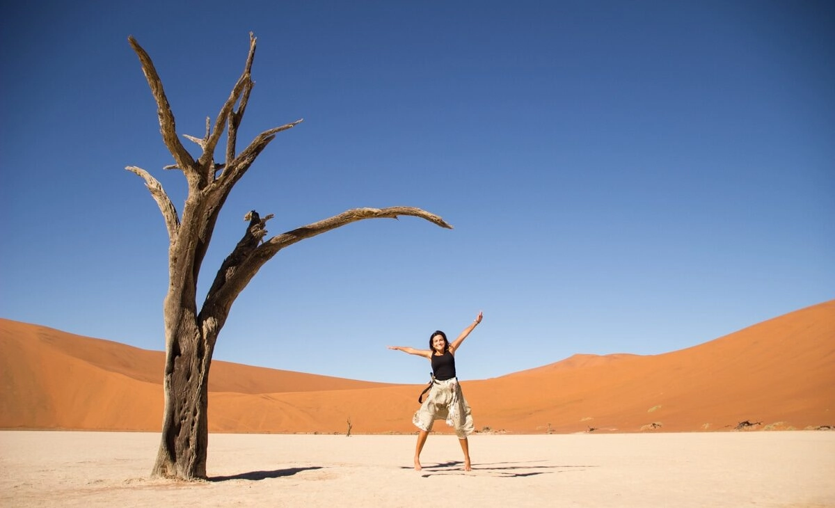 Traveler posing next to tree in deadvlei