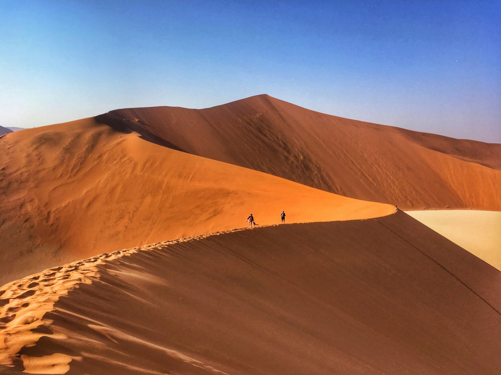 Couple walking through Namibian desert dunes of Sossusvlei