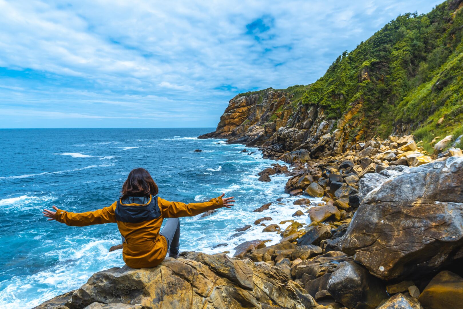 A female model sitting on the shore and looking with satisfaction to the beautiful sea along the Garden Route, South Africa