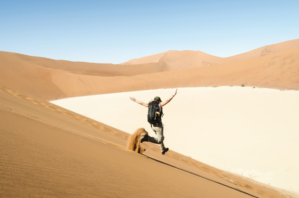 Majestic shot of woman running down a dune on the way to Deadvlei, Namibia