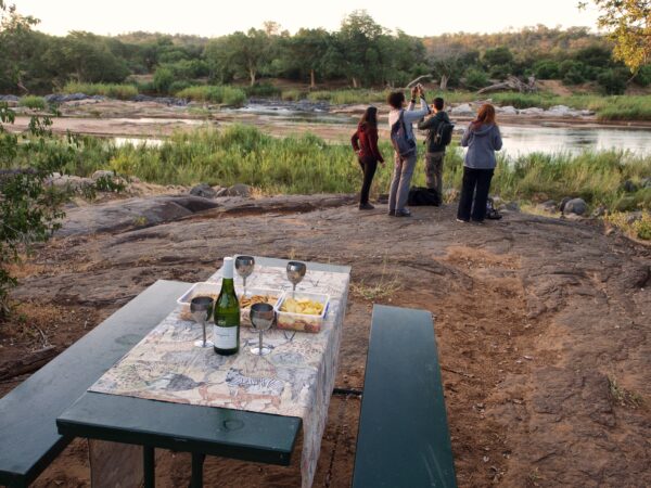 Bush drinks over riverbed with safari guests taking pictures