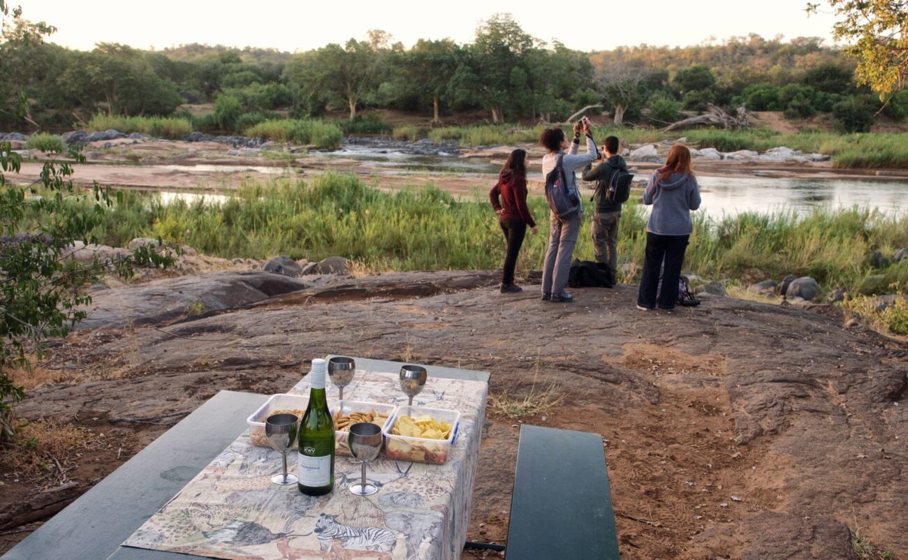 Bush drinks over riverbed with safari guests taking pictures