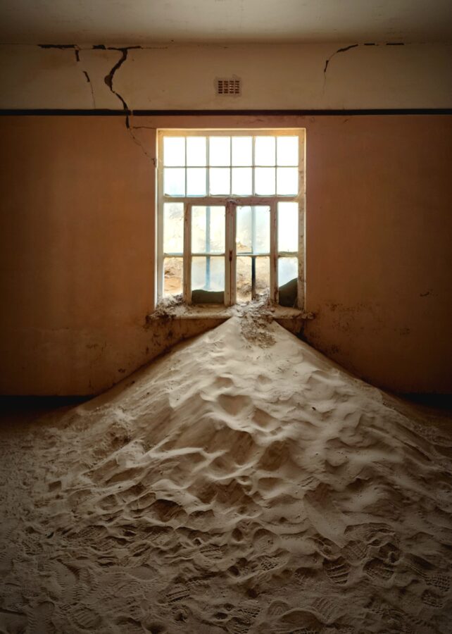 Sand filled room with light shining through window at Kolmanskop.