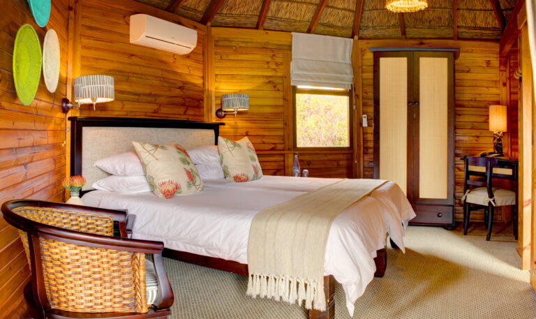 inside of a wooden chalet with a bed, chairs and cupboard