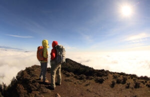 Two hikers enjoy the view on sunrise on mountain peak