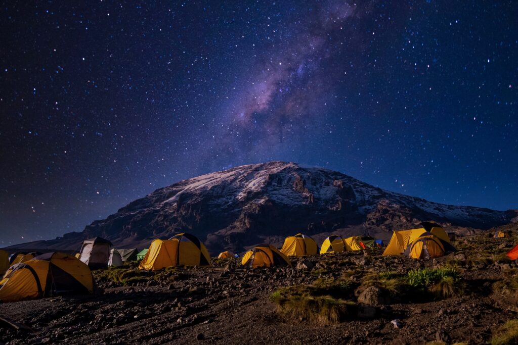 Yellow tents set up on Kilimanjaro at night with starry sky in background
