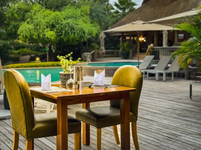 view of a table with chairs on a deck with a swimming pool in the background