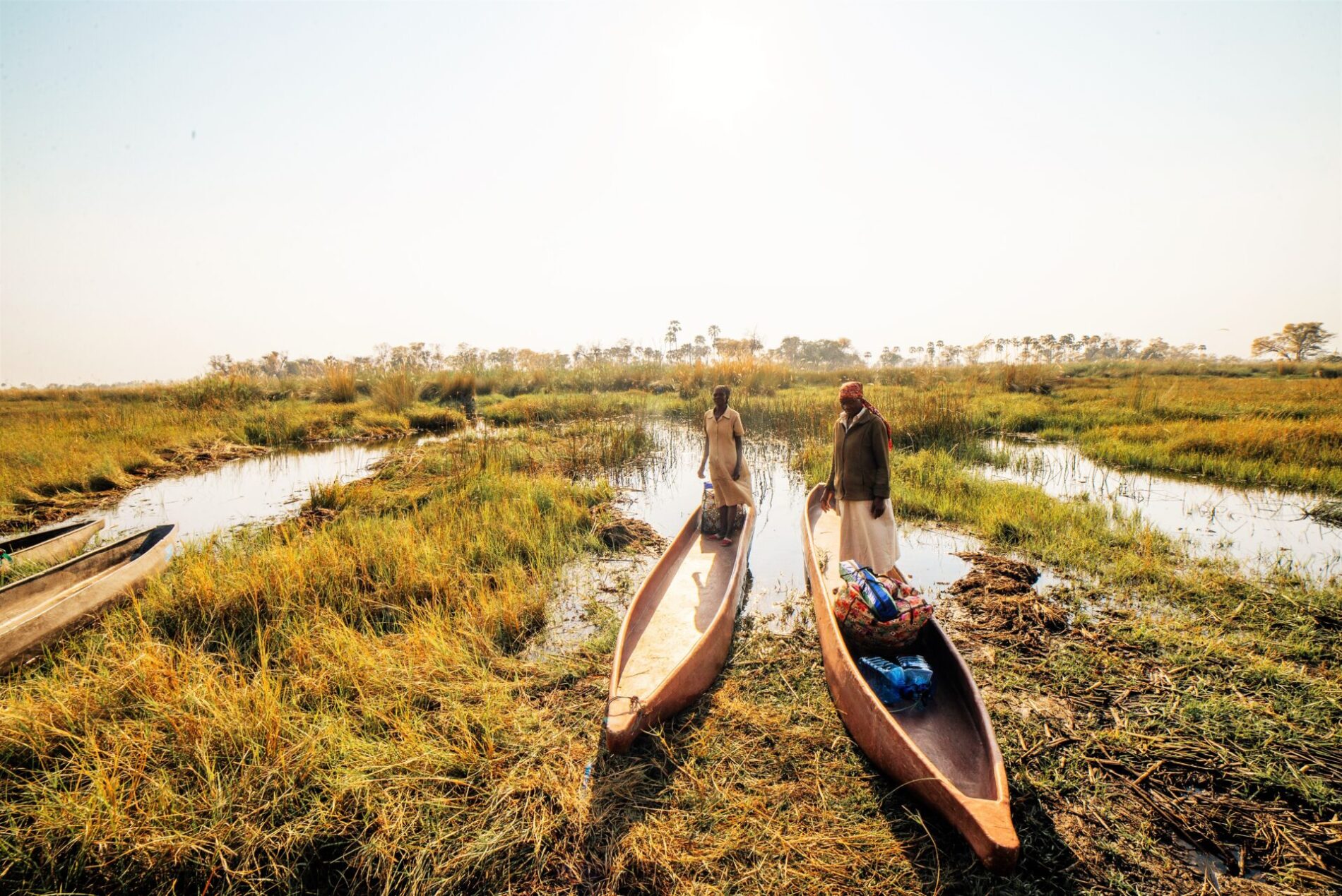 2 people in wooden canoes in the Okavango delta