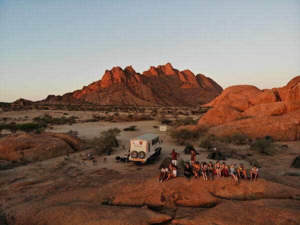 a group of people sitting in the desert in the last sun rays