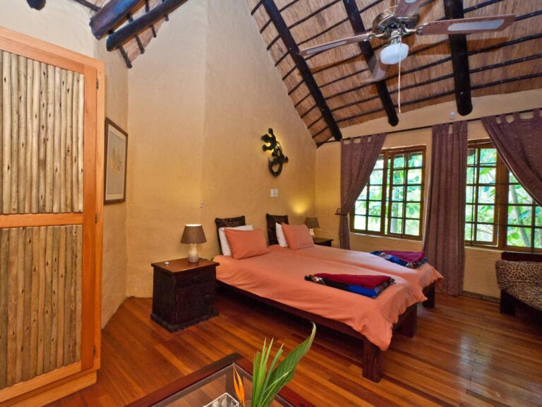 inside of a room with two beds with orange duvets with a gecko light on the wall