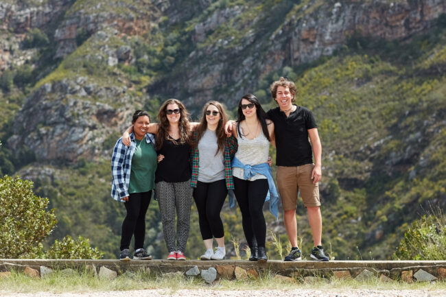 a group of tourists posing in front of a mountain
