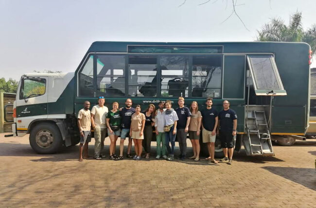 a group of tourists posing in front of a green tour bus