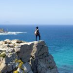 a person standing on a cliff looking out at the ocean