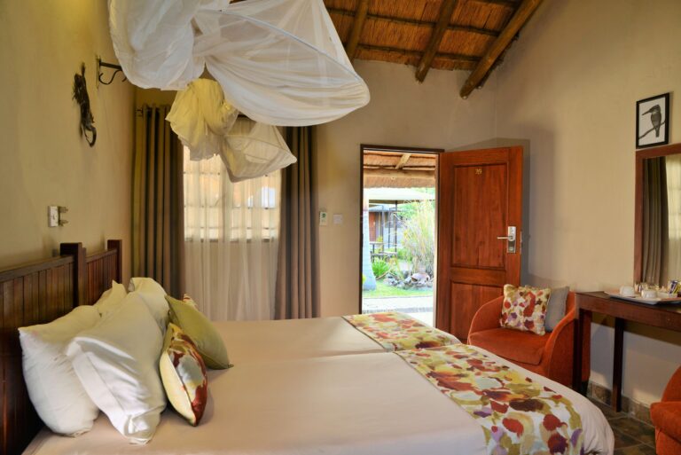 inside of a room with a double bed, mosquito net, chair and coffee station