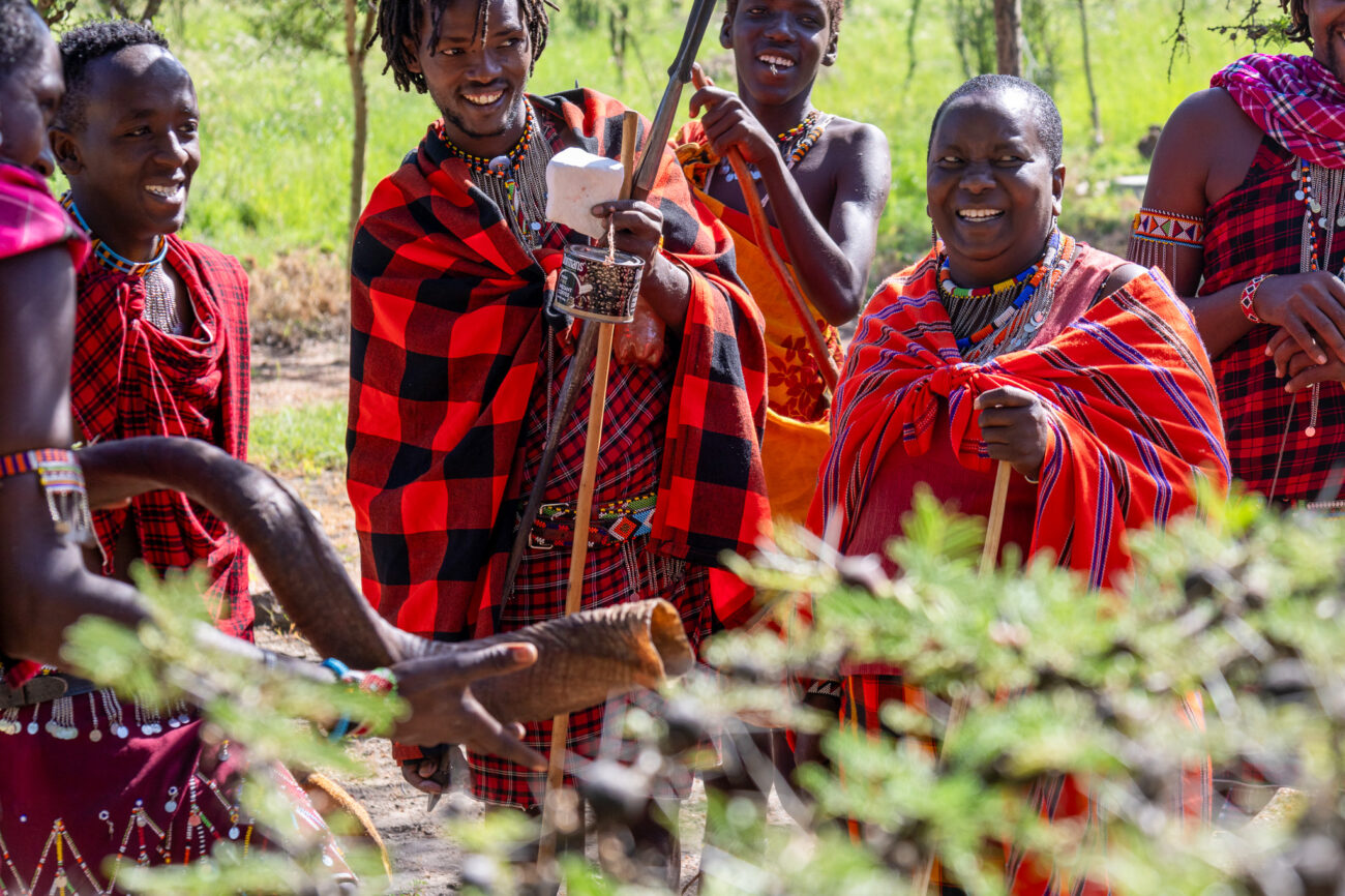 a group of masai people in traditional clothing standing and smiling