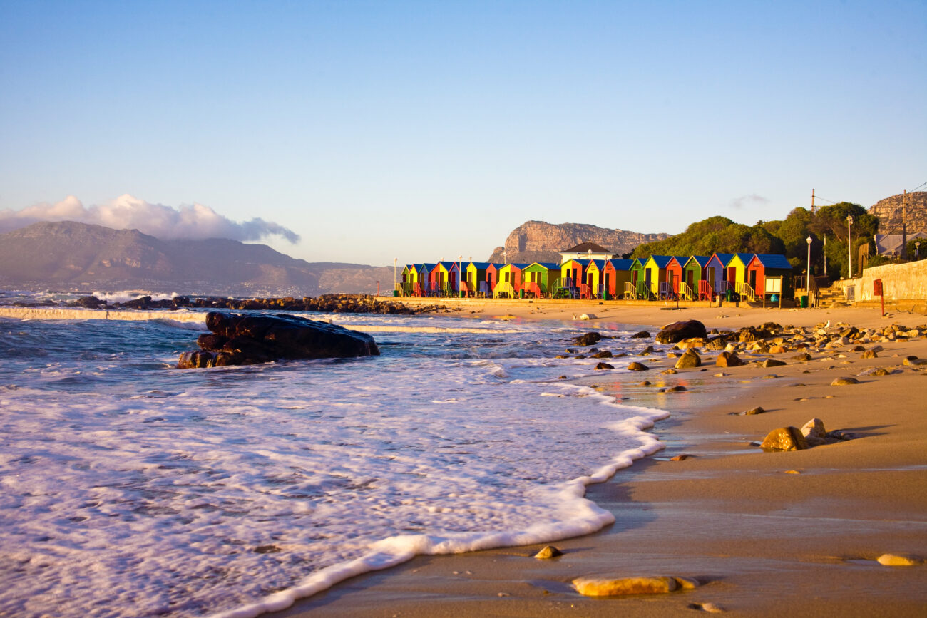colourful houses on a cape town beach with mountains and sea in the background