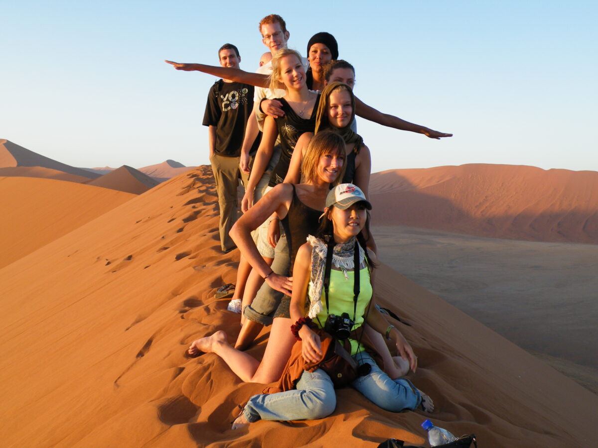 Family lines up for photo on top of dune in Namibia at sunset.